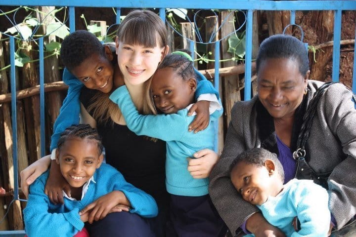 Abby pictured with children in their school uniforms.